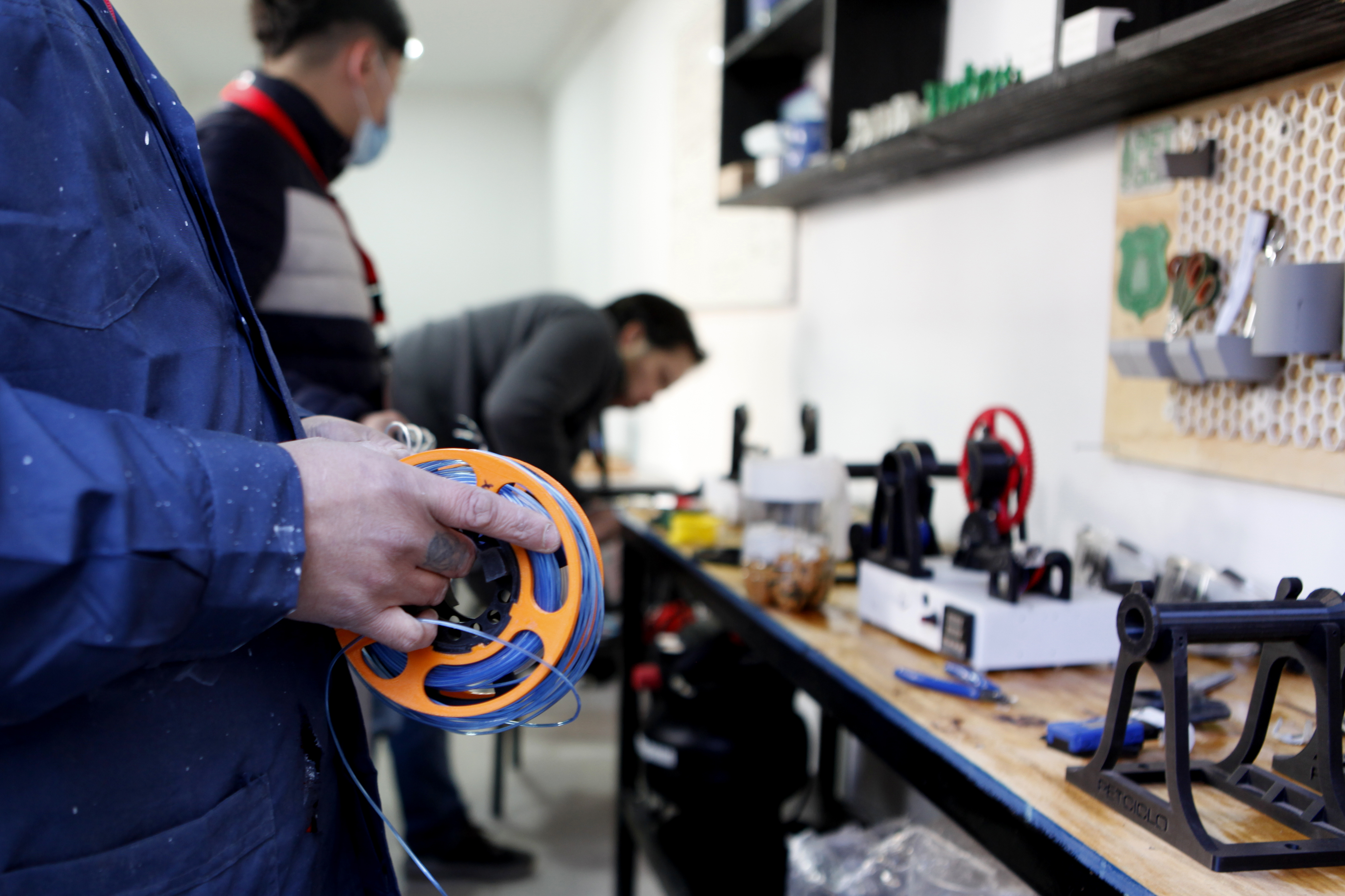 Persona junto a impresora 3D y objetos fabricados con material reciclado